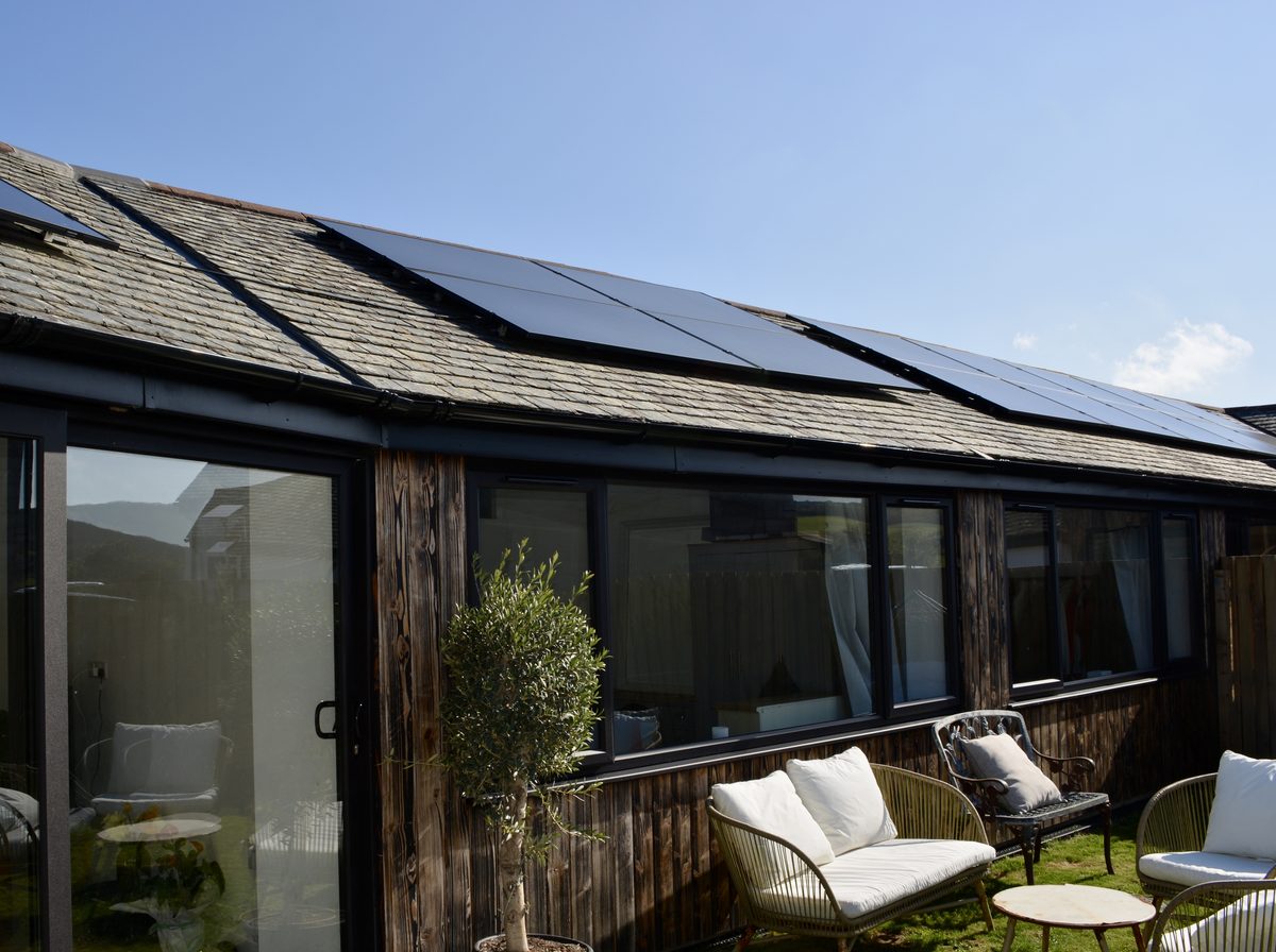 Solar panels across the slate roof of Corva Cottage, seen from the garden terrace below