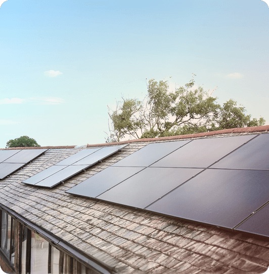 A family outside their home, solar panels visible on the roof above